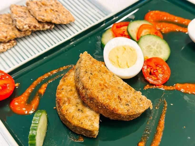 Ouă fierte de găină, chiftea din legume și cereale, roșii cherry, sos Romesco și crackerși